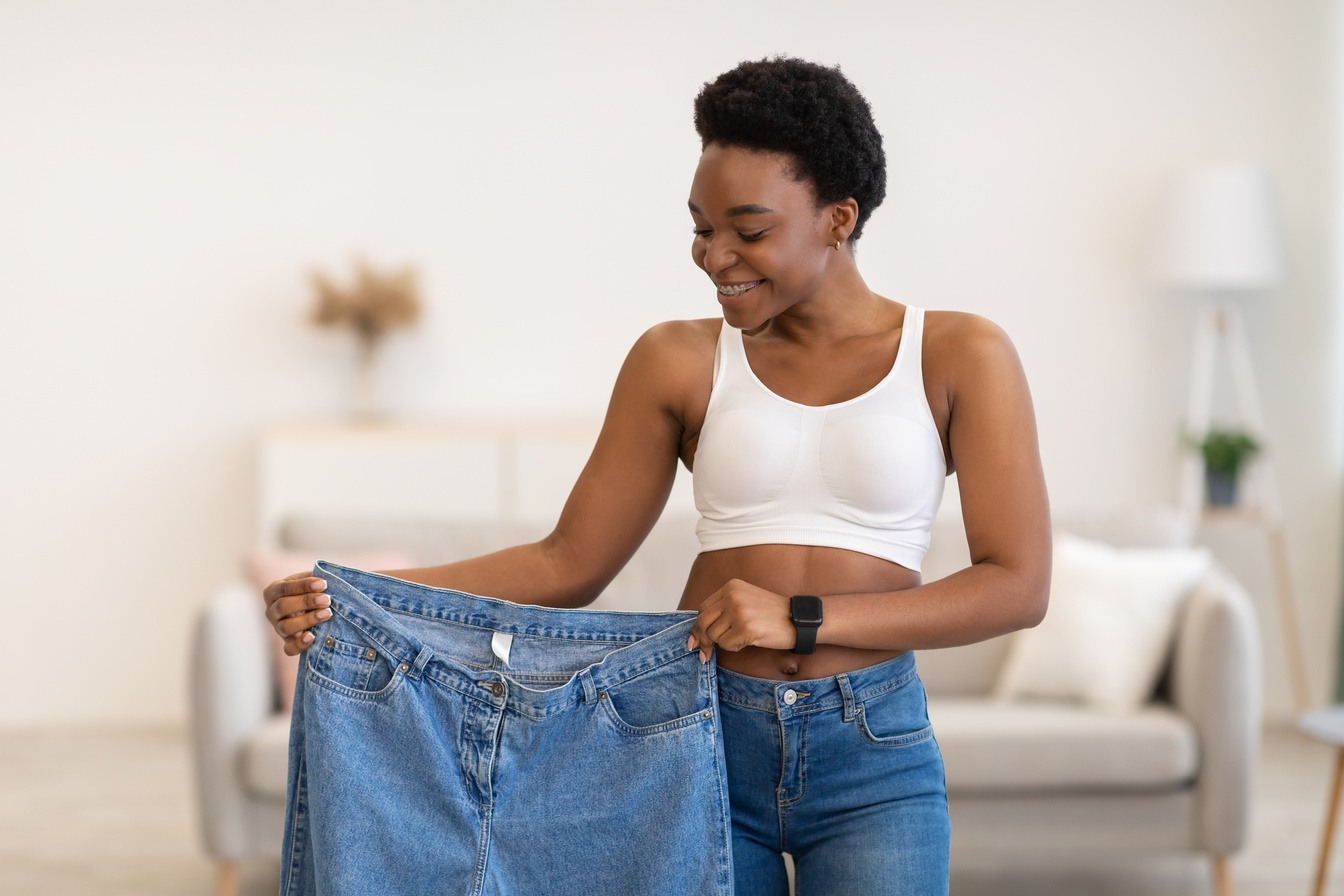 Black Lady Holding Jeans Too Big After Weight-Loss At Home